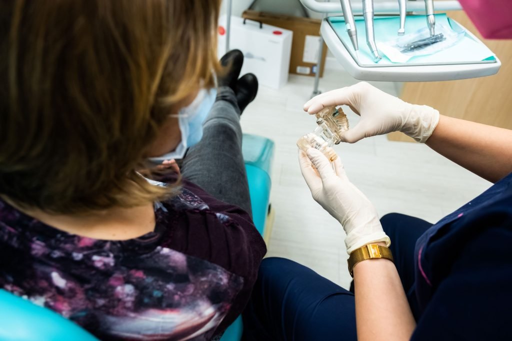 Mujer adulta colocándose una funda transparente (alineador) para enderezar los dientes